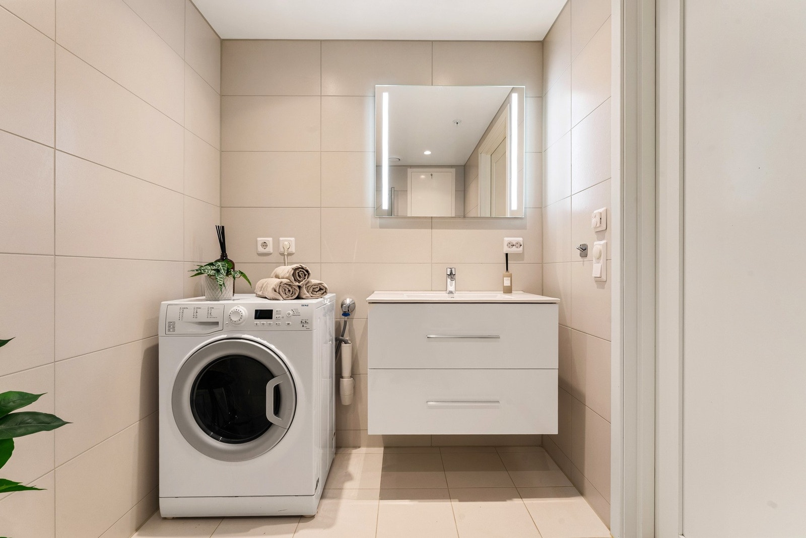 Badet inneholder: Foldedører i dusj, veggtoalett og baderomsinnredning med heldekkende servant samt belyst speil. Opplegg for vaskemaskin. Galleribilde