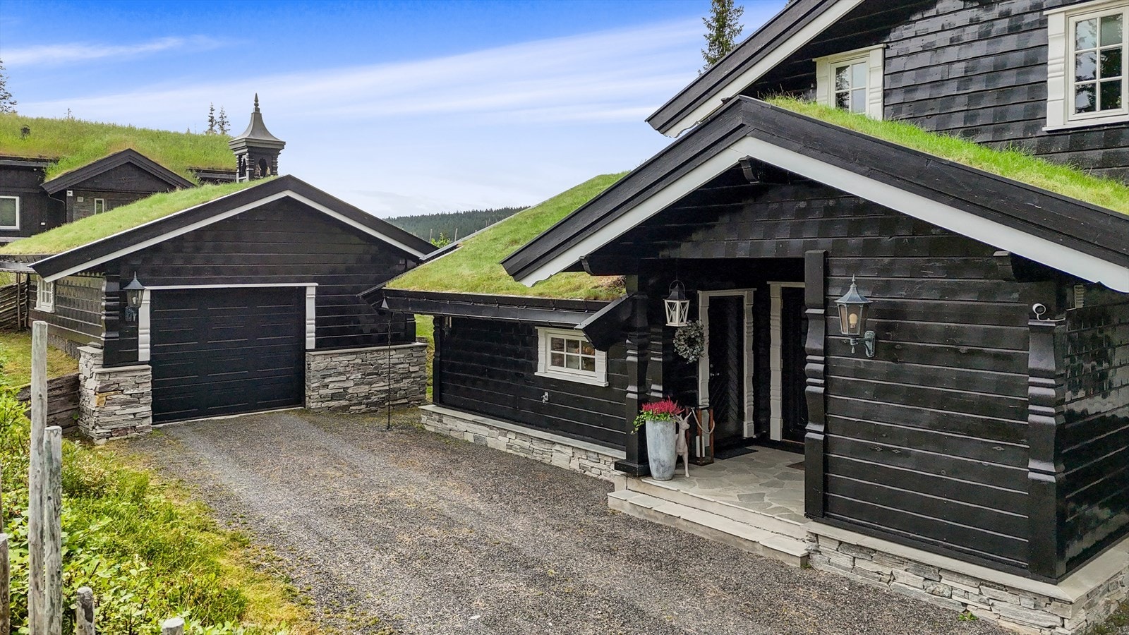 Velholdt hytte i hugget panel med flott arkitektur og et håndlaget klokketårn i kobber over garasjen Galleribilde