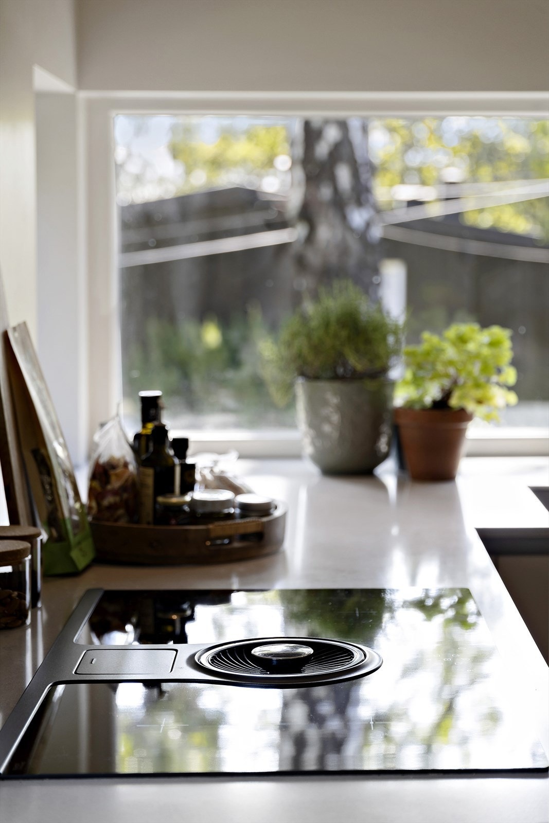 Benkeplate i stein med underlimt vask og nedfelt platetopp med integrert ventilator. Løsningen er både minimalistisk og plassbesparende Galleribilde