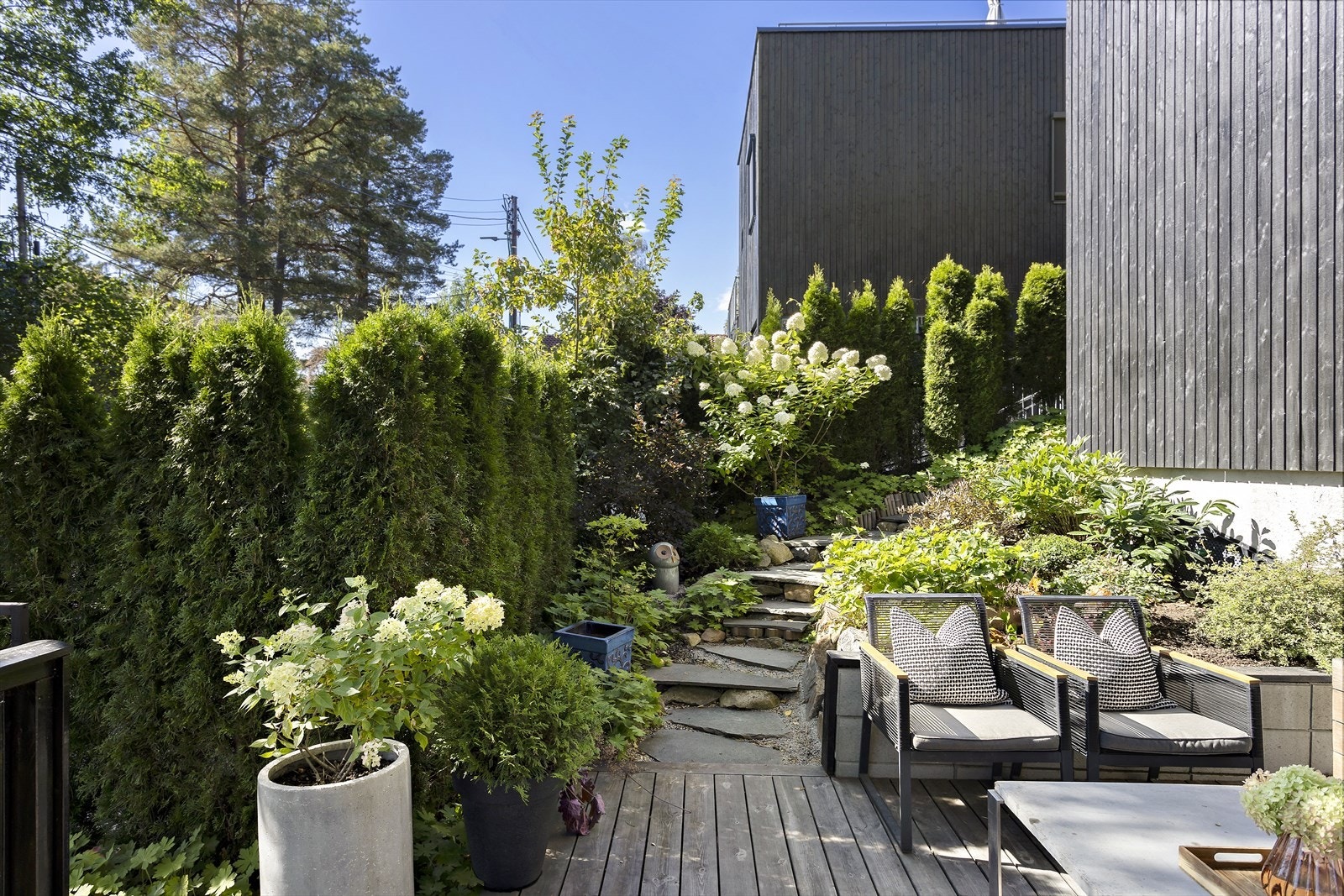Frodig og fint med rikelig beplantning. Fra terrassen er det hellelagt gangvei opp til boligens inngangsparti Galleribilde