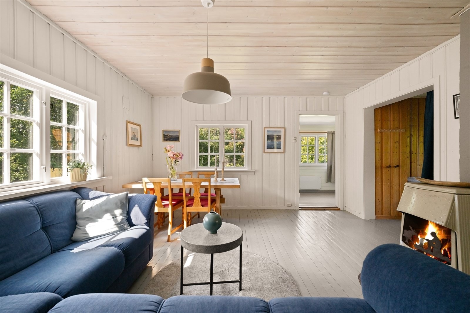 Stuen har mye av den klassiske hyttefølelsen intakt, med panelte overflater, sprossevinduer og en lun vedovn. Galleribilde