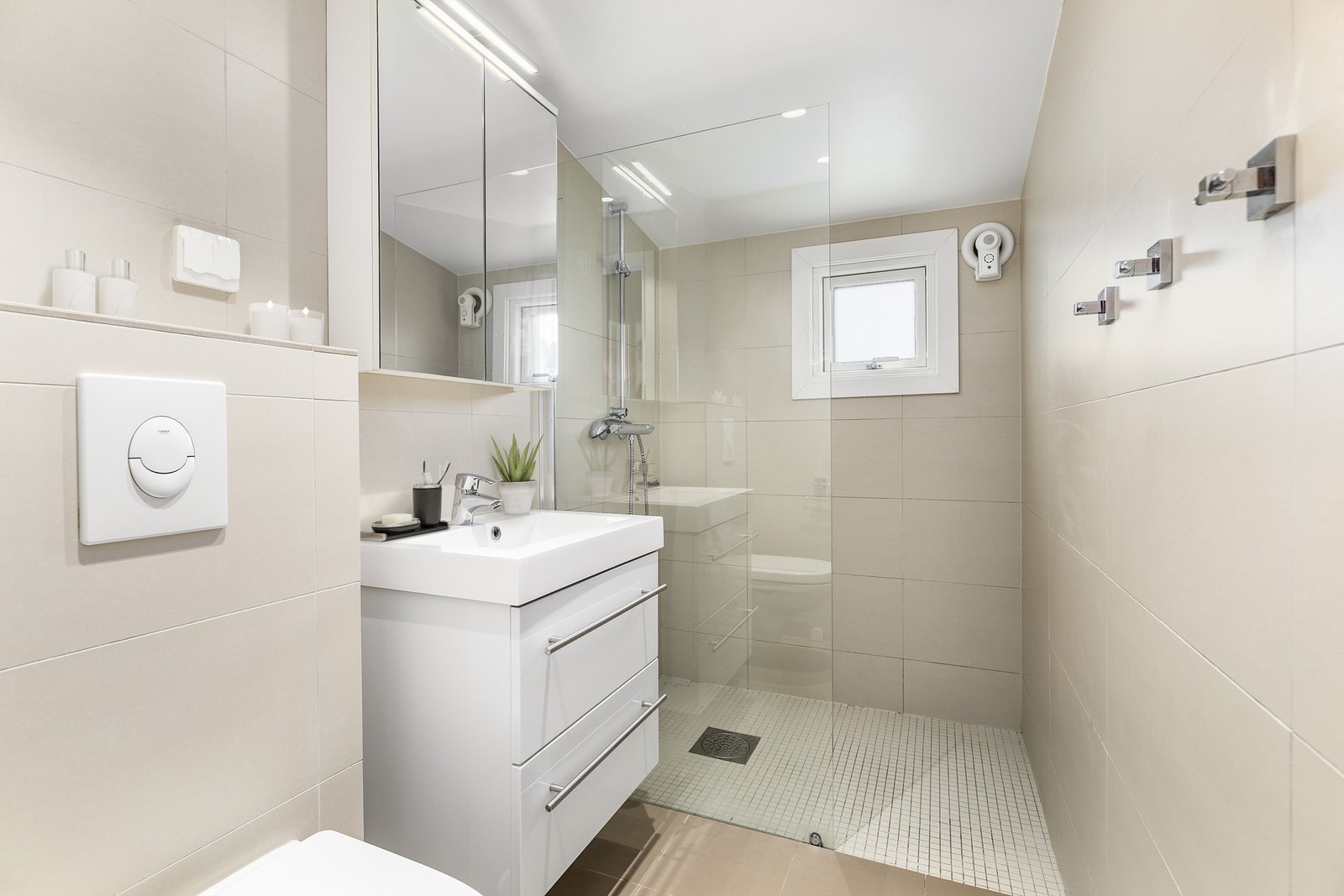 Badet ble renovert/fornyet i 2016 og har gulvvarme. Gulv og vegger er utført med fliser, himlingen med innfelte spotter. Bildet er digitalt stylet. Galleribilde