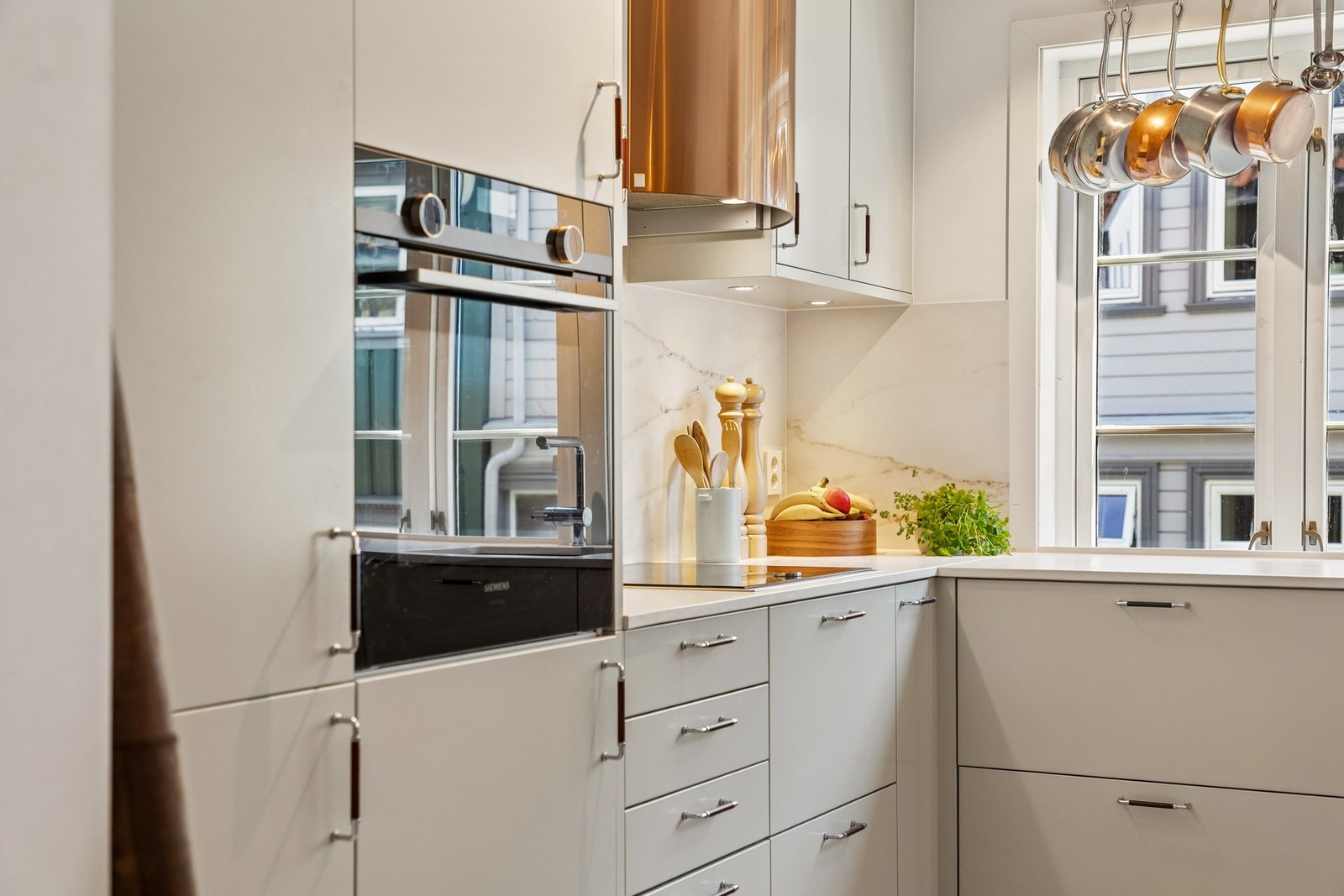 Kjøkkenet er fra Drømmekjøkkenet og har en gjennomført utførelse med integrerte hvitevarer, stilrene fronter og elegante detaljer. Benkeplater og sprutplater i Dekton, kombinert med Røroshetta i børstet kobber, bidrar til et helhetlig og påkostet uttrykk. Galleribilde