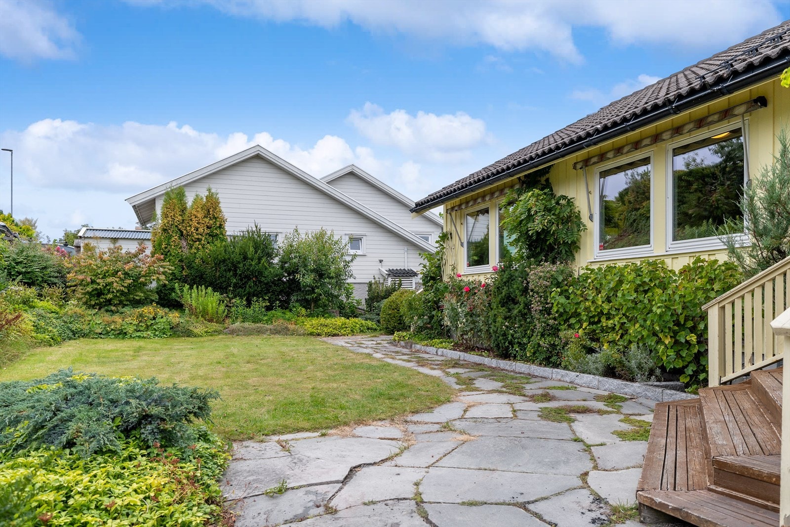 Velstelt hage med et rikt utvalg av planter, busker og frodige beplantninger. Galleribilde