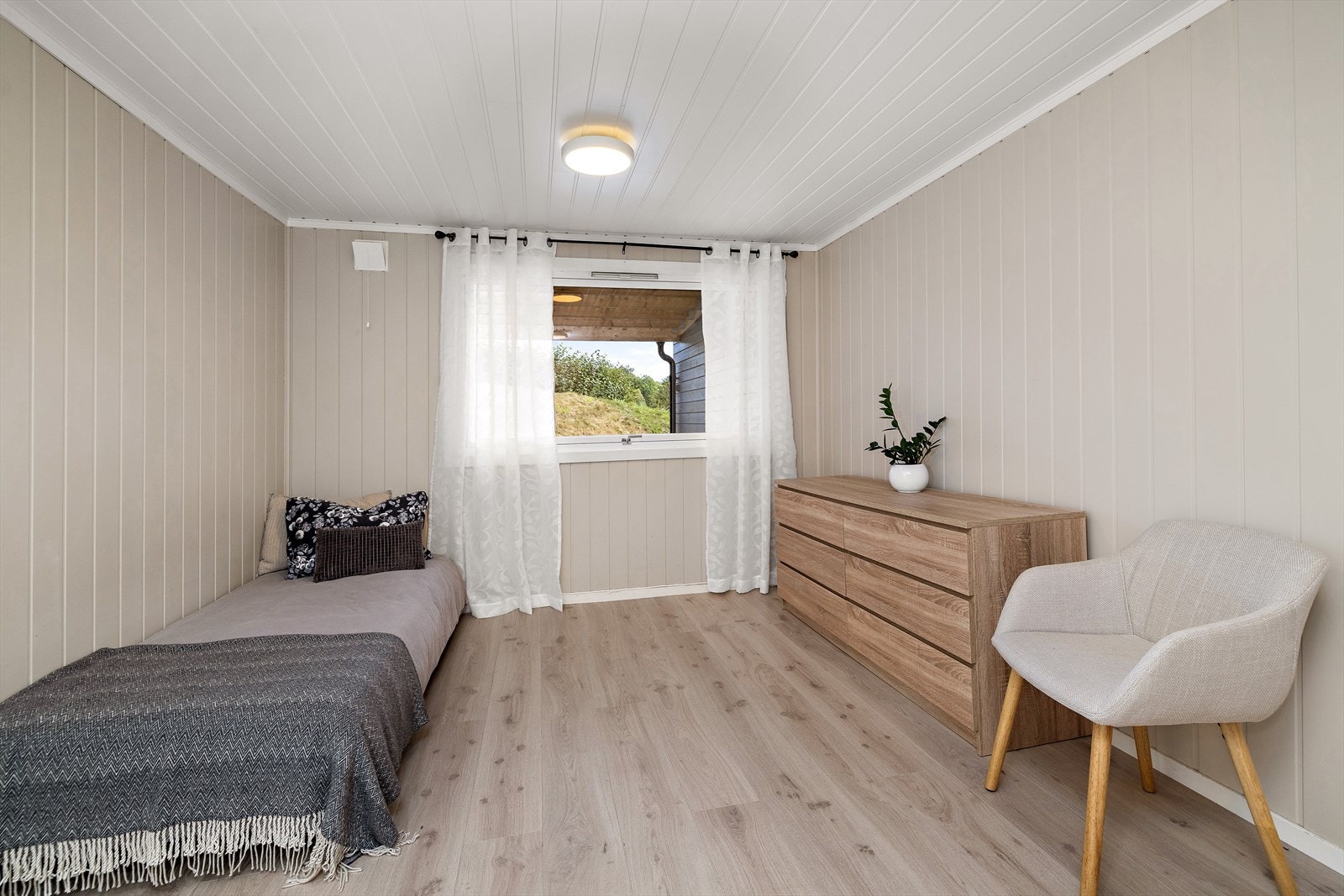 Rommet har panel på veggene og laminat på gulvet. Galleribilde