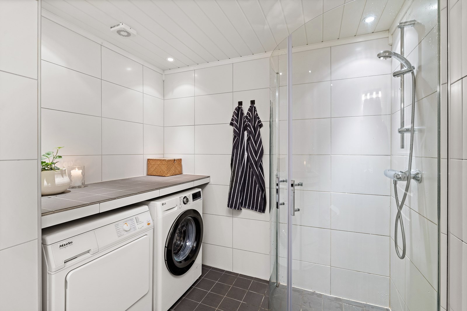 Badet har dusjhjørne med glassdører og opplegg for vaskemaskin og tørketrommel. Galleribilde