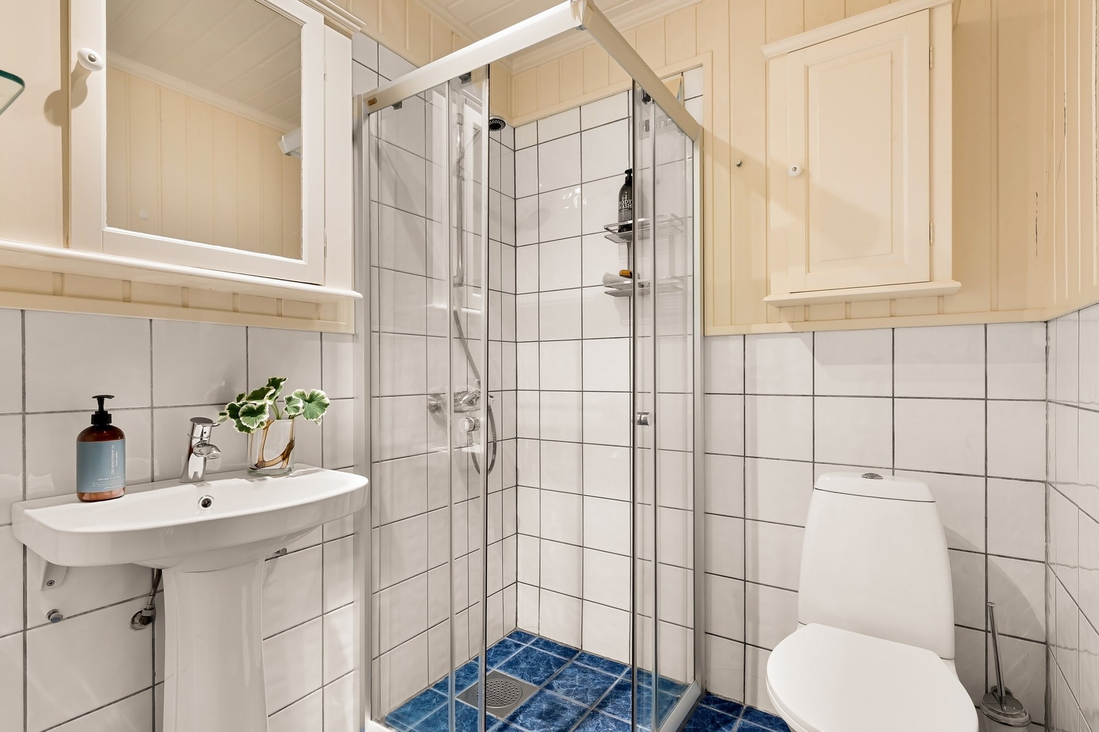 Bad tilknyttet utleiedelen mot øst. Badet har flislagt gulv med gulvvarme, en kombinasjon av panel og flis på veggene samt et praktisk dusjhjørne. Galleribilde