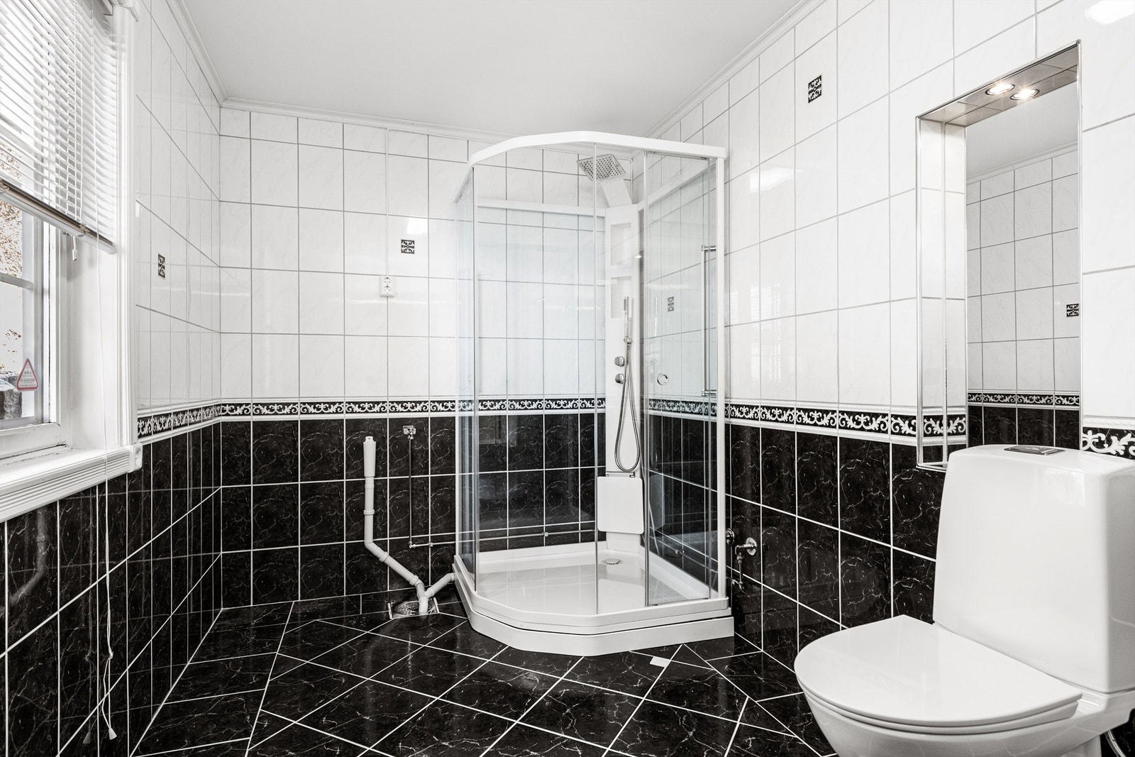 Badet har flislagt gulv med gulvvarme, dusjkabinett og opplegg for vaskemaskin. Galleribilde