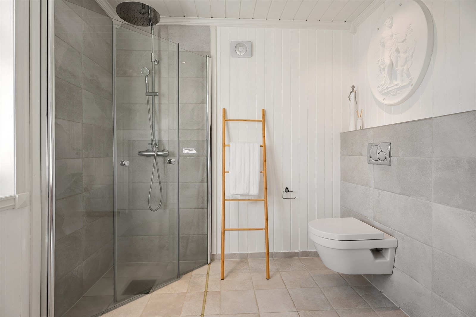 Badet har vegghengt toalett og dusjhjørne med glassvegger. Galleribilde