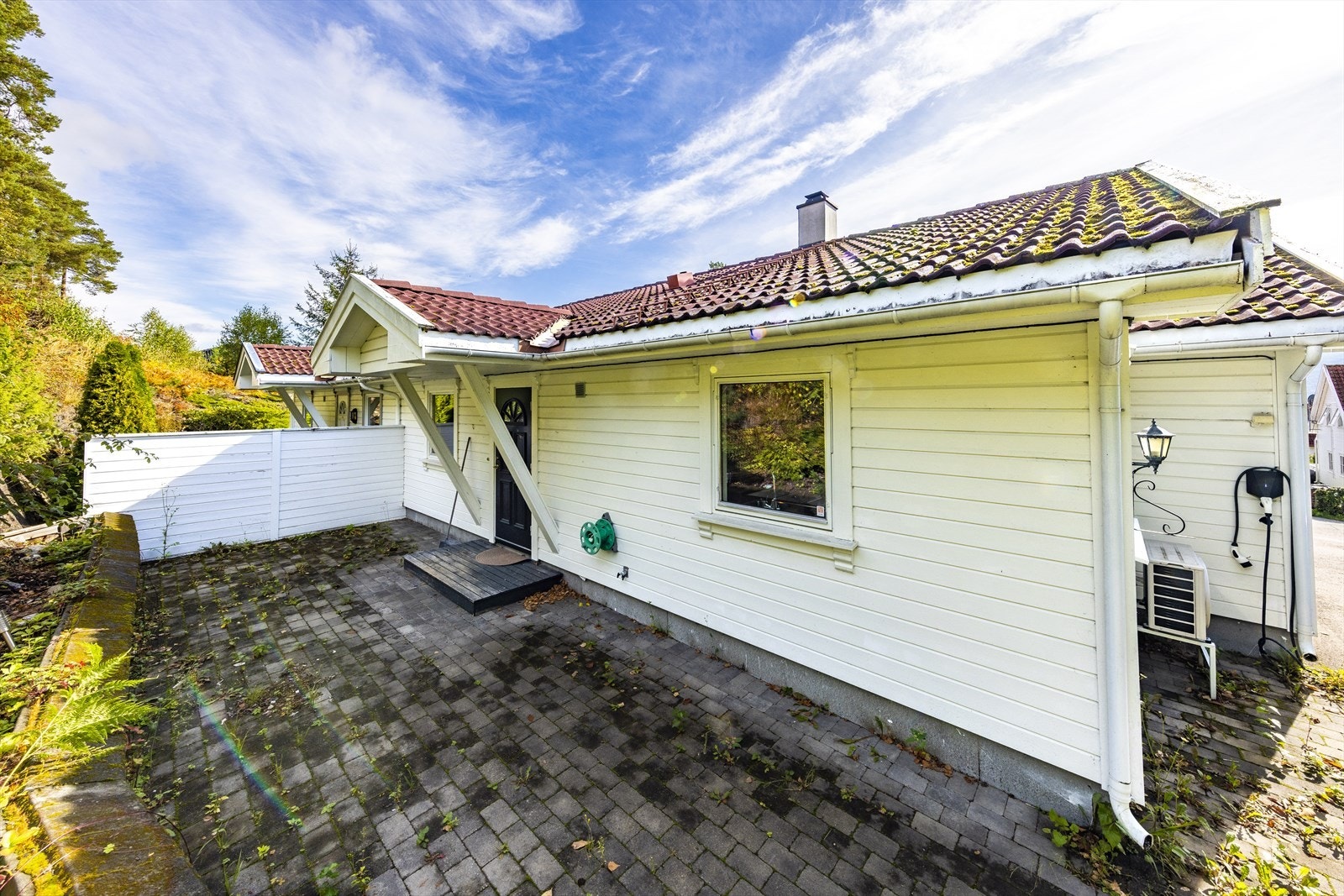 Inngangspartiet har takoverbygg og uteplass med belegningsstein. Galleribilde