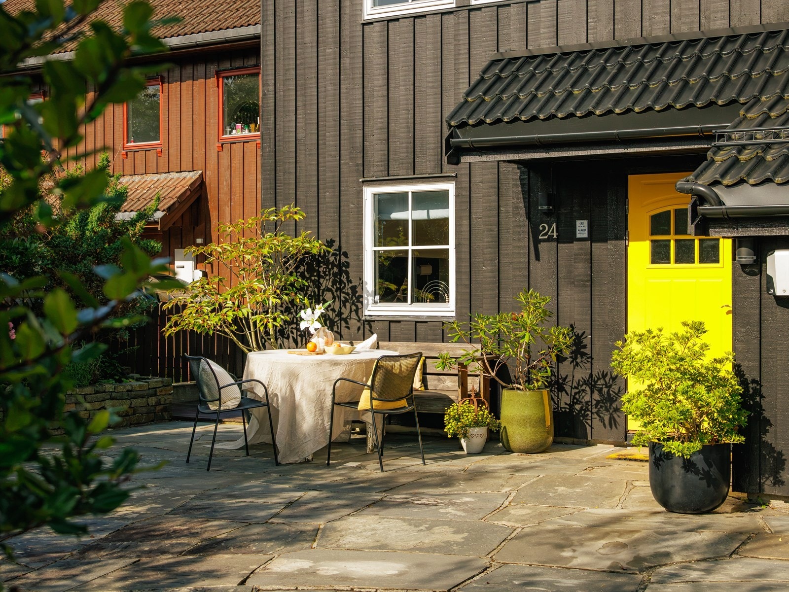 Flott opparbeidet hage med stor skiferplatting med plass til sittegruppe og oppstillningsplass for biler. Fine natursteinsmurer med bed og beplantning. Galleribilde