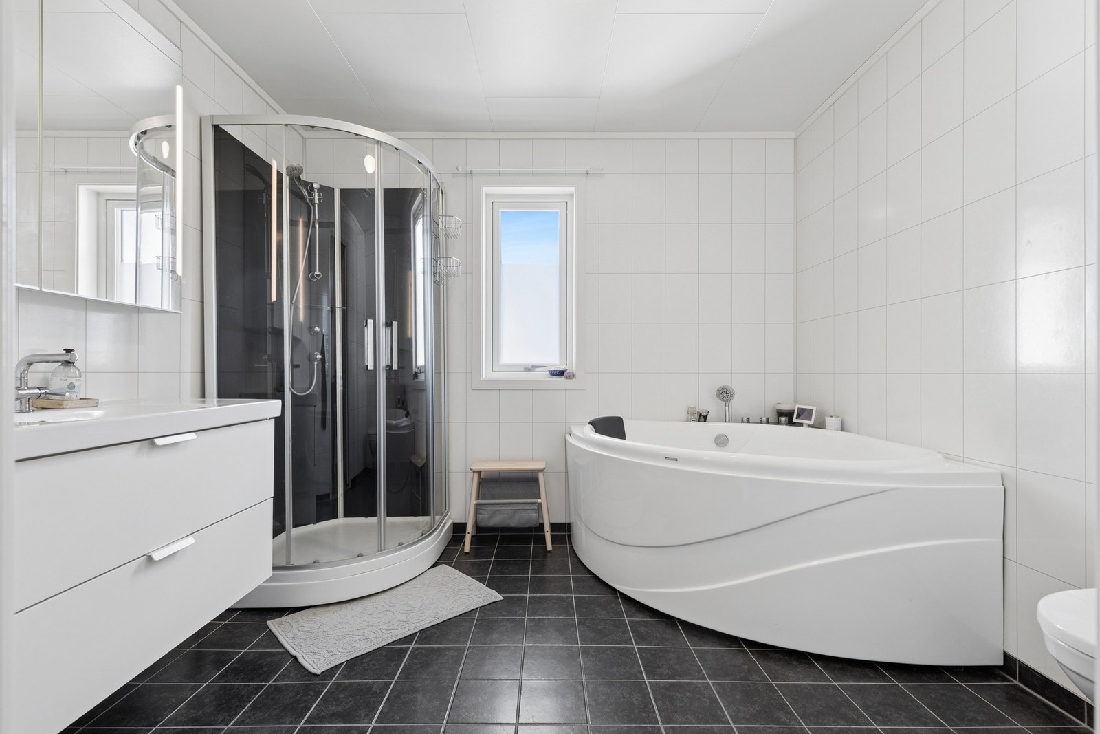 Badet har flislagt gulv med elektriske varmekabler og vegger med baderomsplater. Galleribilde