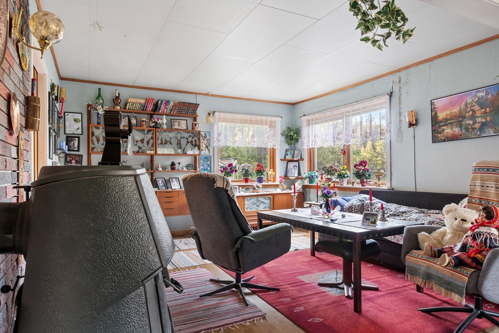 Det er store vindusflater som slipper inn rikelig med dagslys - Vedovnen skaper hygge og ikke minst rask oppvarming på kjølige dager Galleribilde