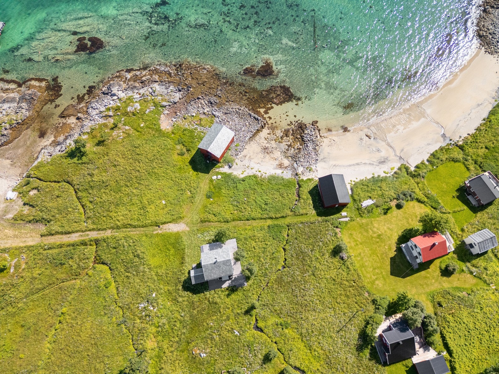 Hovedhuset ligger flott plassert i terrenget med sjøen og stranden like nedenfor.