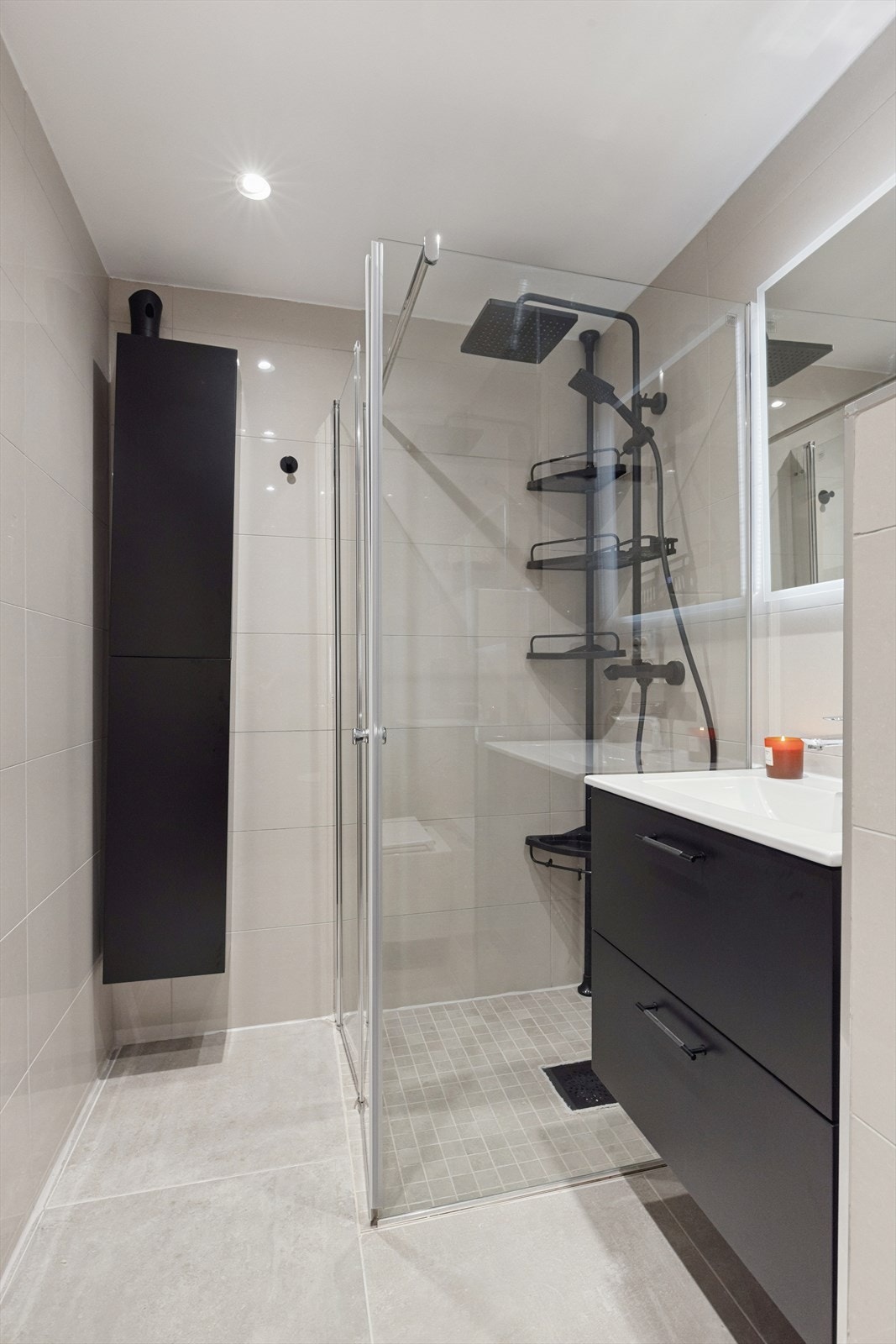 Badet er innredet med innfellbare dusjvegger i herdet glass, regnfalldusj, vegghengt toalett og servant med skuffeinnredning Galleribilde