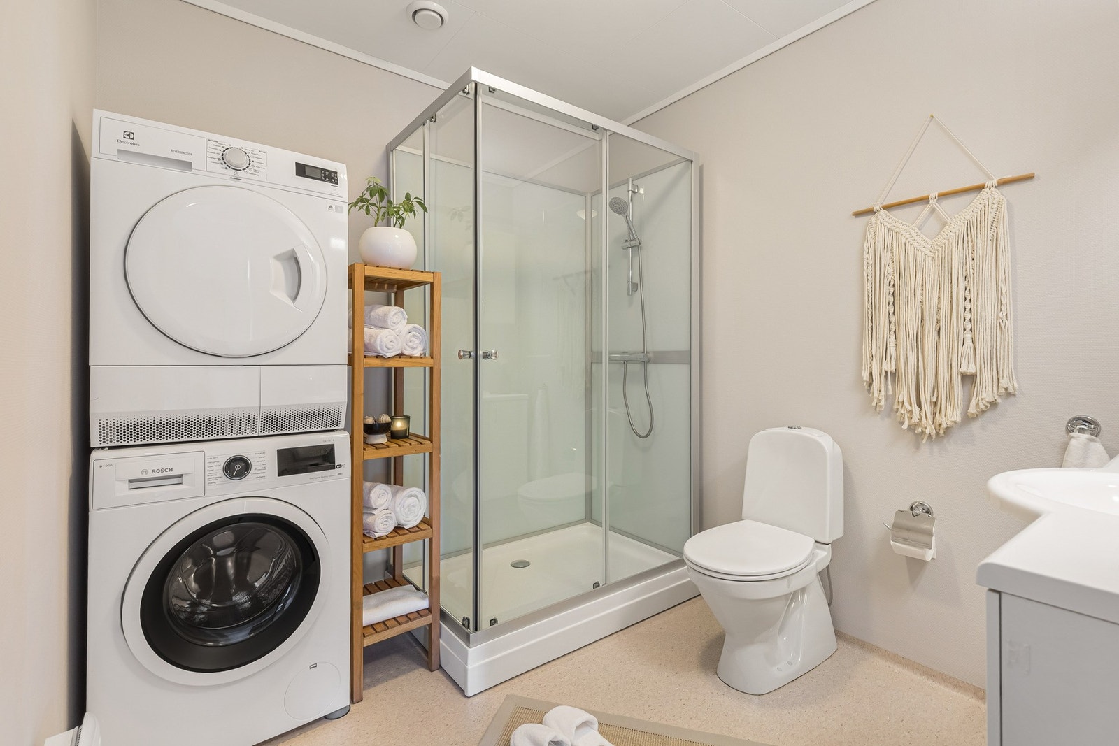 Badet har praktisk plass til både vaskemaskin og tørketrommel, i tillegg til servantinnredning, toalett og dusjkabinett. Galleribilde