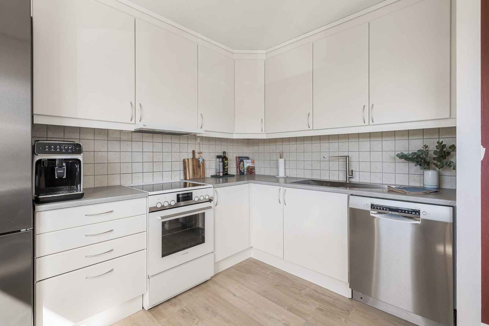 Kjøkken med hvite, glatte fronter, mørk benkeplate og ventilator med avtrekk ut. Galleribilde