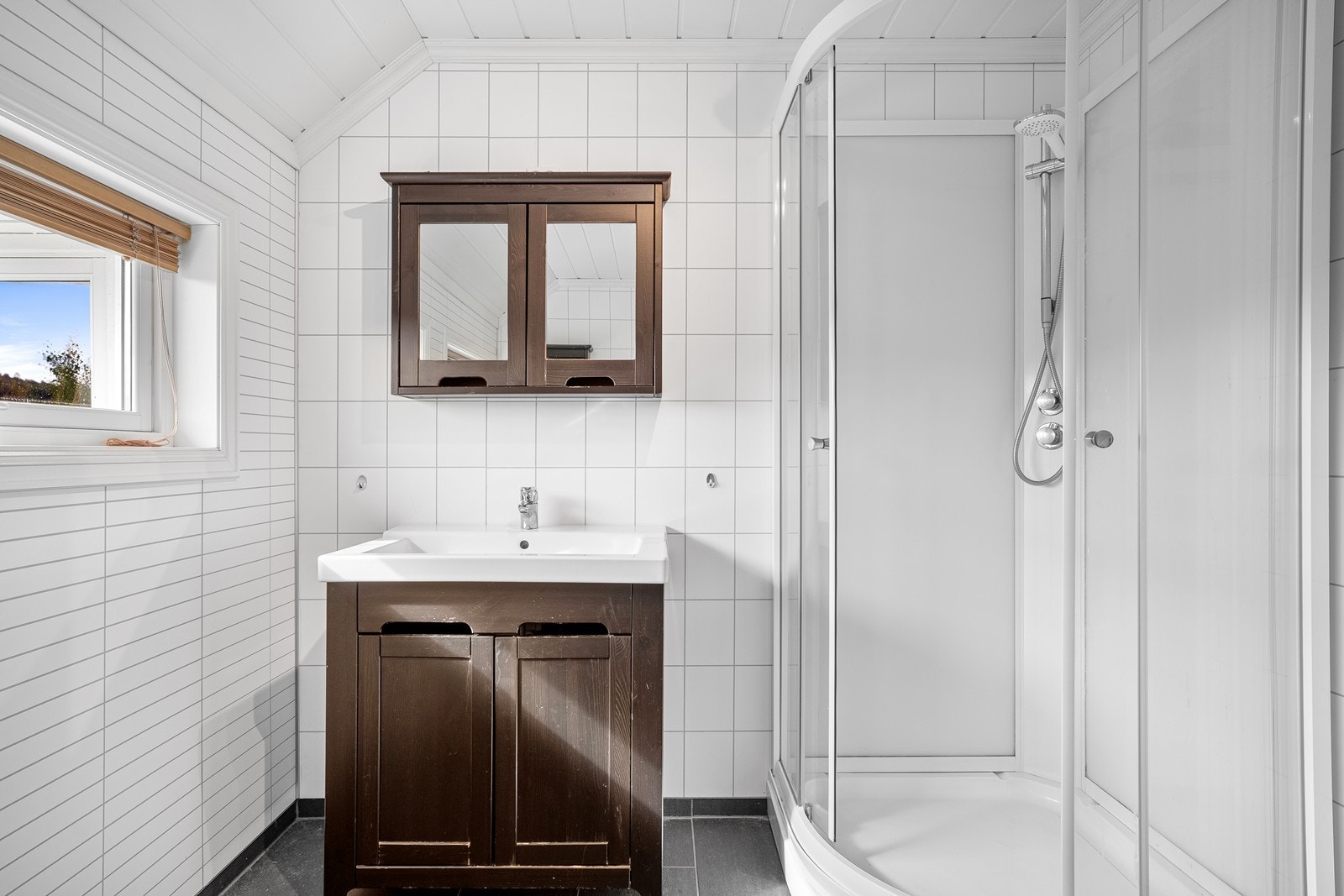 Badet er utstyrt med dusjkabinett, servant med oppbevaring og speilskap. Galleribilde