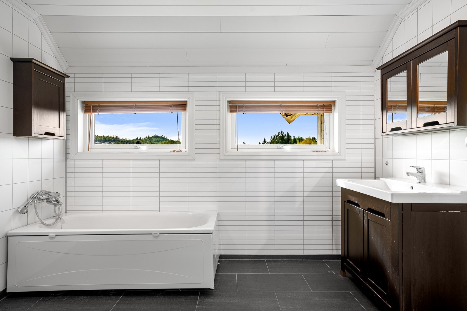 Romslig bad med badekar, servantinnredning og vinduer som sørger for godt med naturlig lys. Galleribilde