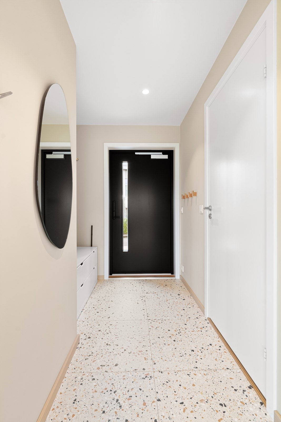 Lys og innbydende entré med flotte terrazzo fliser på gulv og plass til å henge fra seg yttertøy. Galleribilde