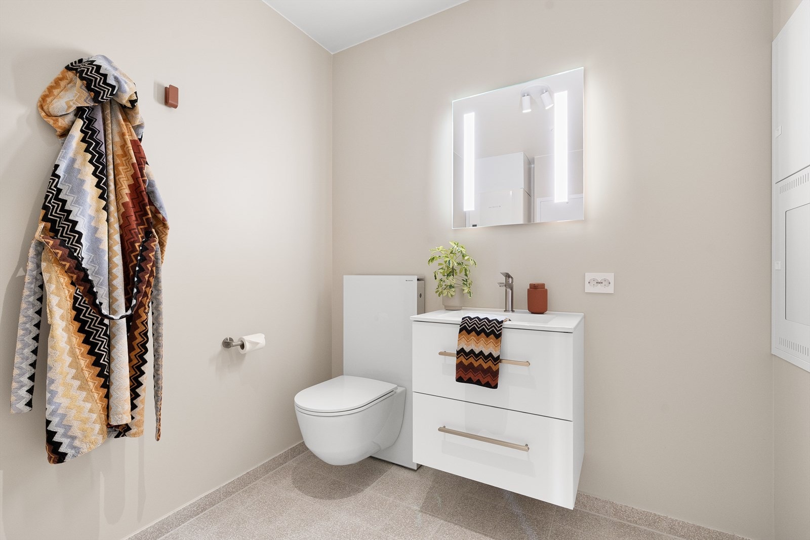 Badet har vegghengt toalett, hel servant, speil med belysning, opplegg til vaskemaskin og ekstra oppbevaringsplass i baderomsmøbel. Galleribilde