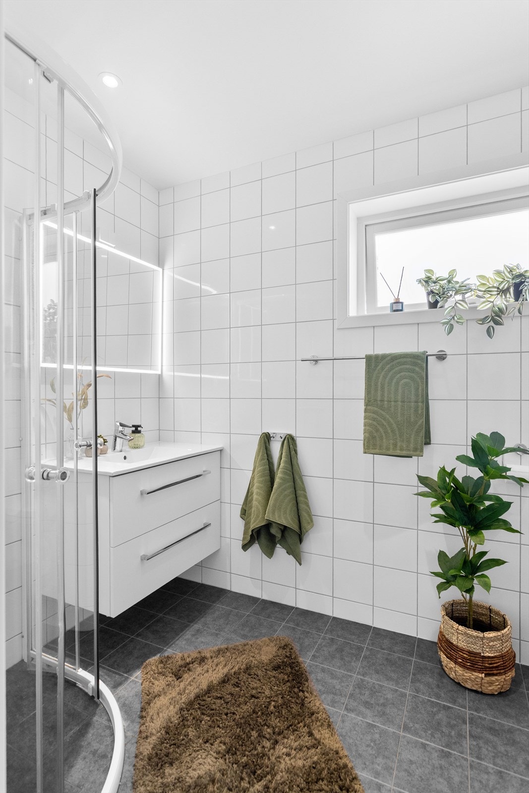 Badet har flislagt gulv med gulvvarme og dusjhjørne med glassdører. Galleribilde