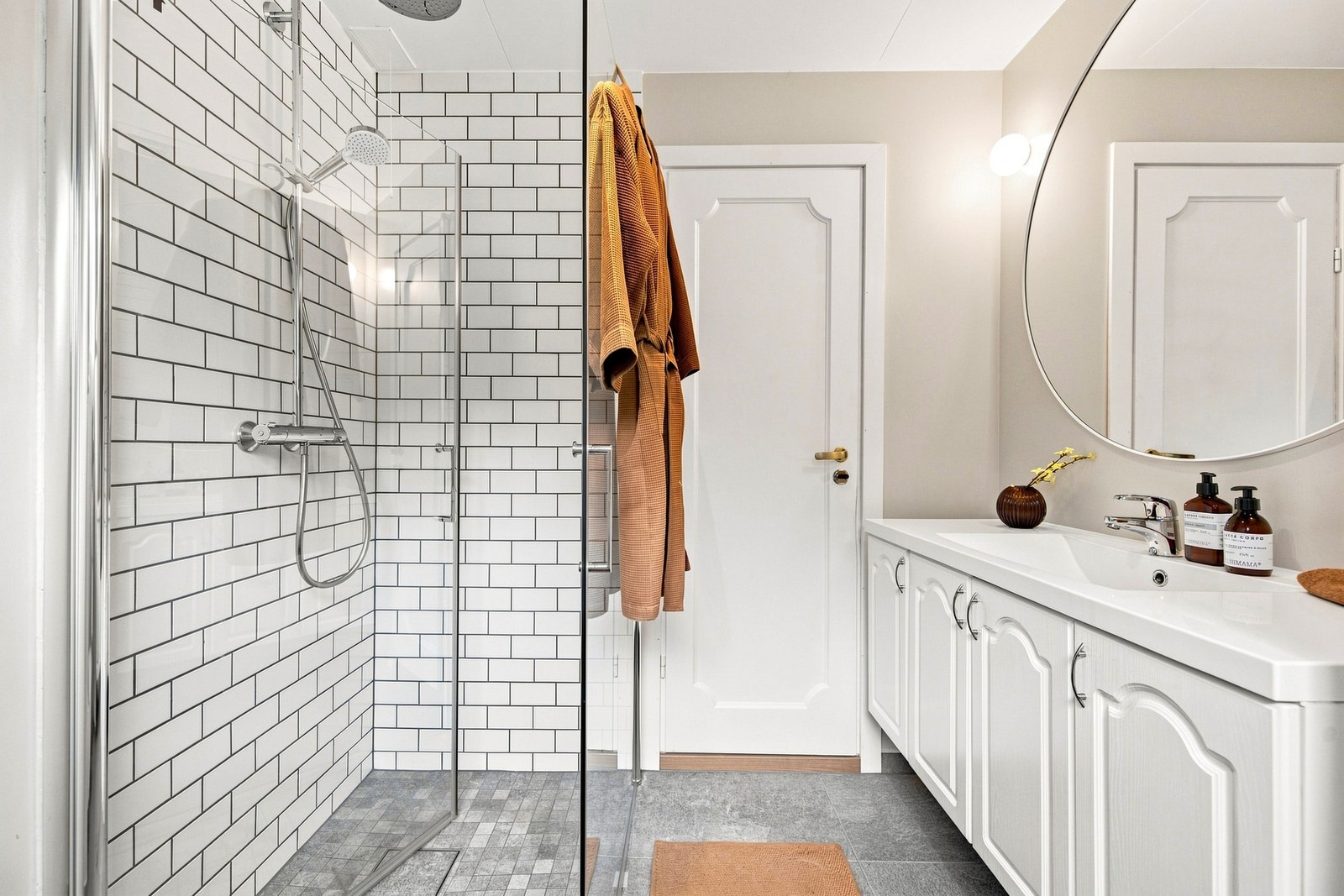 Badet er innredet med servantmøbel, speil med belysning, vegghengt toalett og innfellbart dusjhjørne i glass. Galleribilde