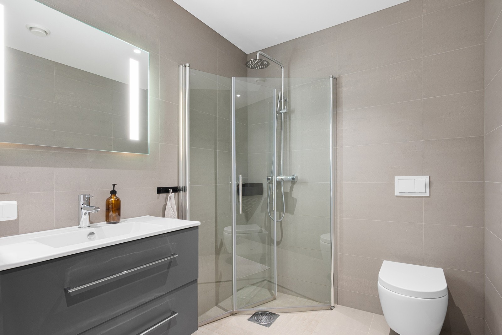 Badet fremstår delikat med flislagte overflater, gulvvarme og downlights i himling. Galleribilde