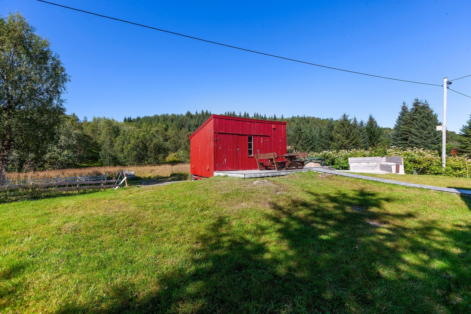 Romslig og solrik naturtomt med uthus, fine uteplasser og god plass til lek og aktiviteter. Galleribilde