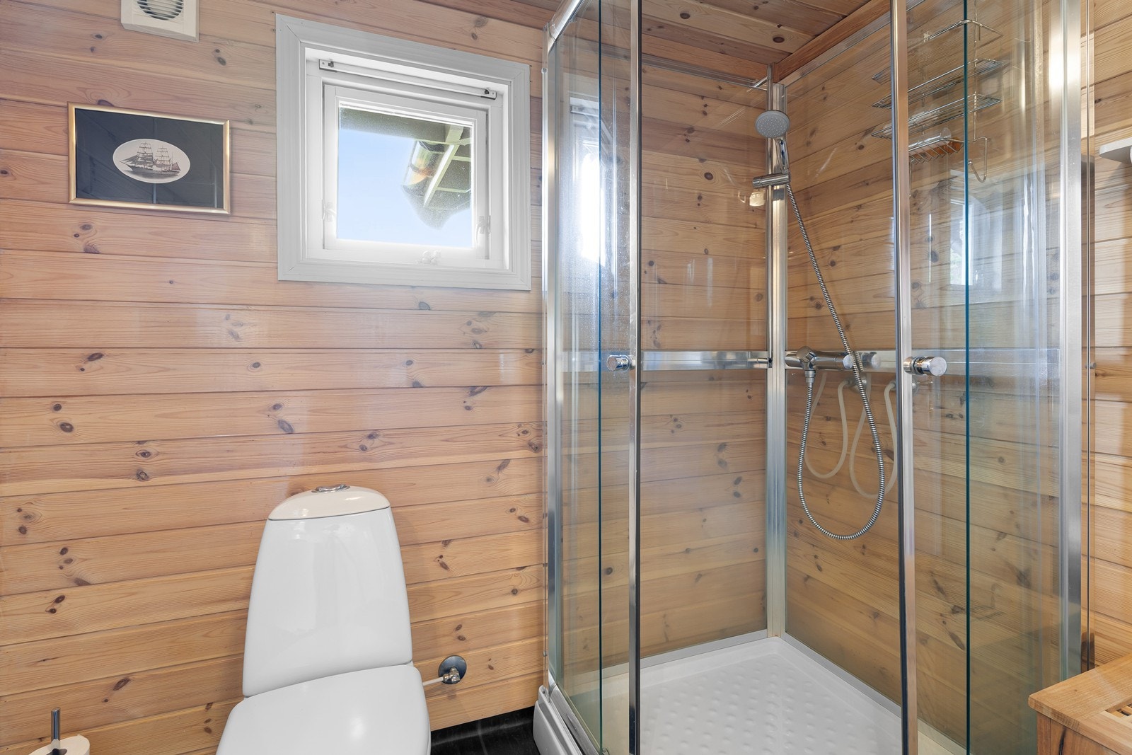 Badet er videre innredet med gulvstående toalett og dusjkabinett. Galleribilde