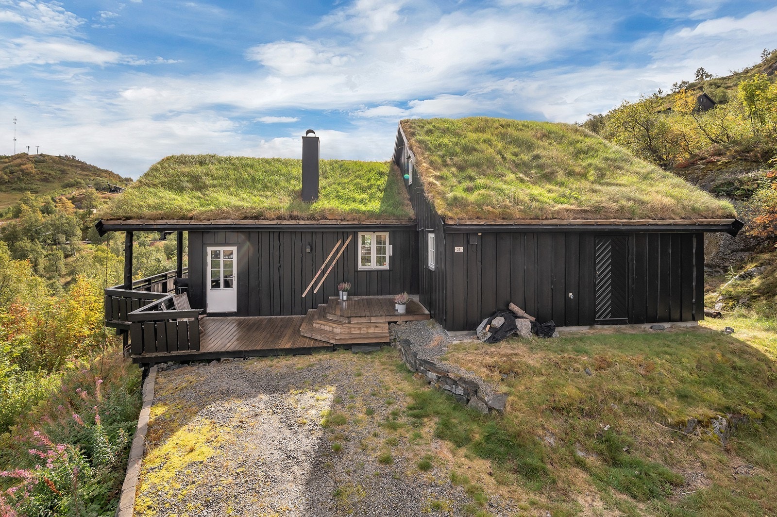 Fasaden er kledd med stående villmarkspanel, og taket er tekket med torv, noe som gir hytta et robust og tradisjonelt uttrykk som harmonerer godt med omgivelsene. Galleribilde