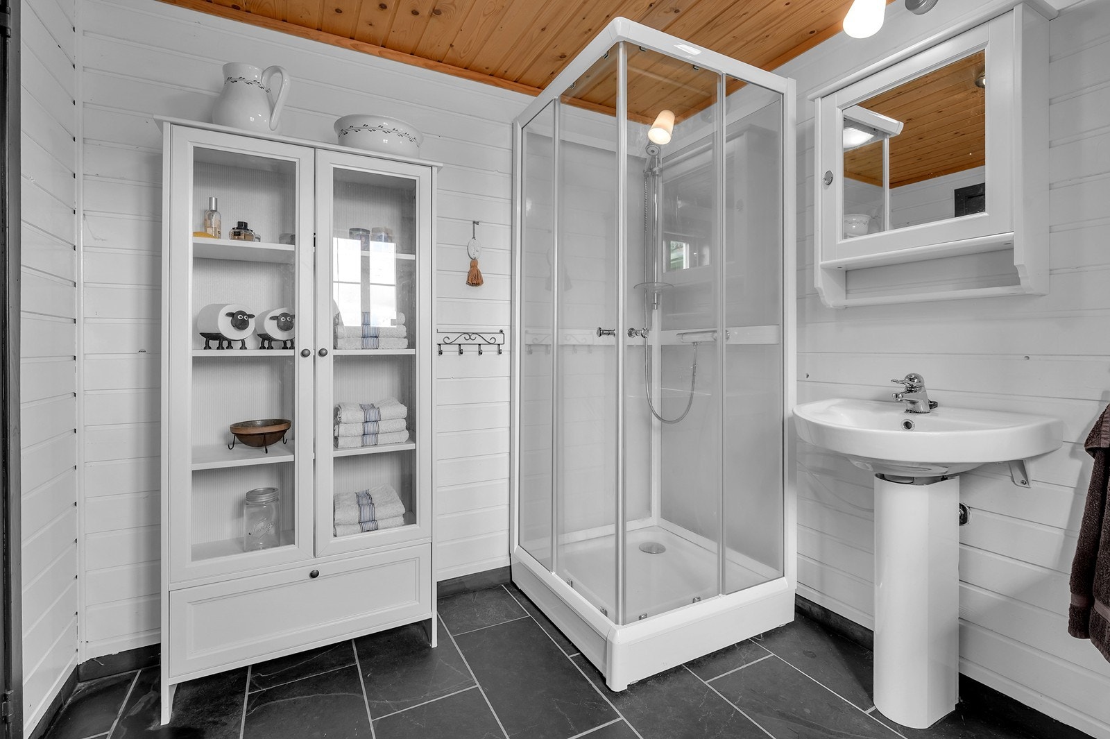 Badet/Vaskerom har flislagt gulv med gulvvarme, dusjkabinett og vegghengt servant, noe som gir et praktisk og lettstelt baderom med god komfort. Galleribilde