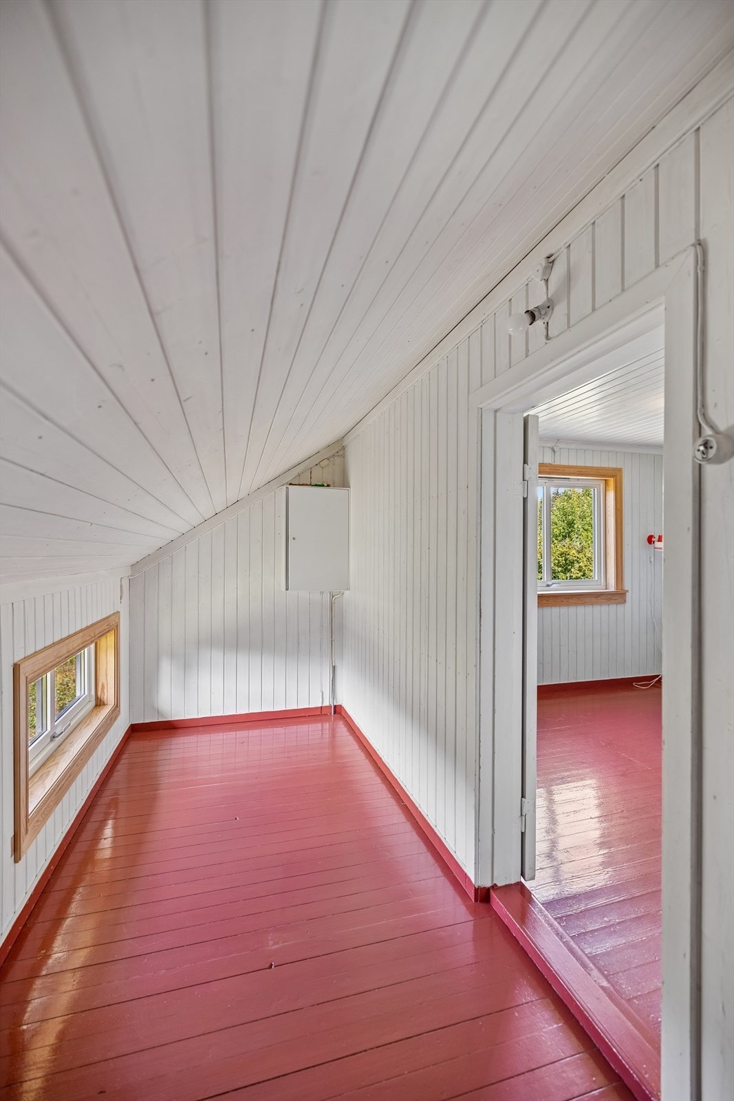 Kott med malt tregulv og skråtak med hvitmalt panel. Galleribilde