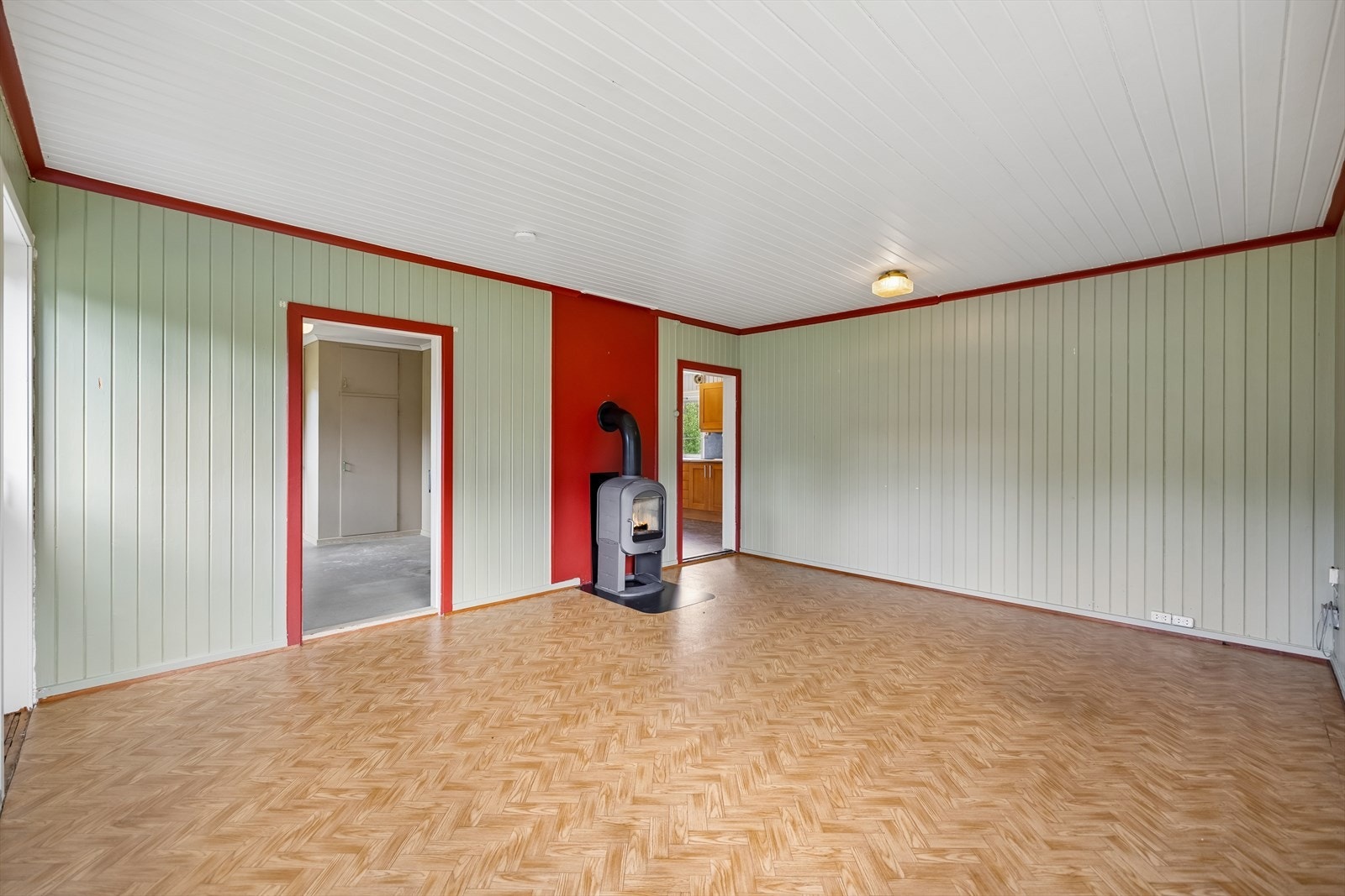 Romslig stue med panelte vegger og himling i trepanel. Galleribilde