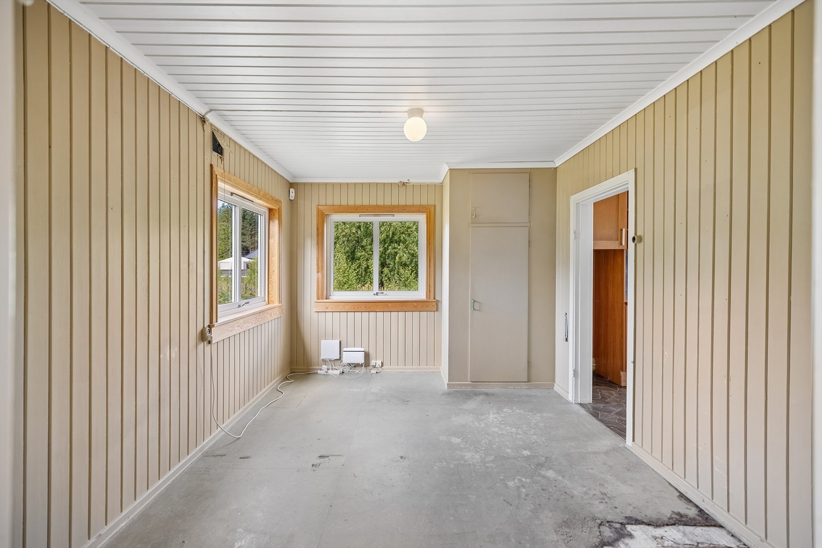 Rommet har vinduer på to vegger og panelte overflater. Galleribilde