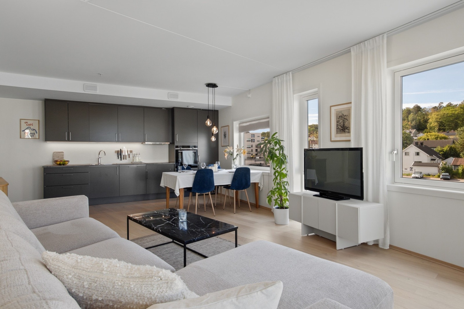 Kjøkkenet er integrert i stuen med gjennomgående mørke fronter, som gir en helhetlig og moderne fargepalett. Galleribilde
