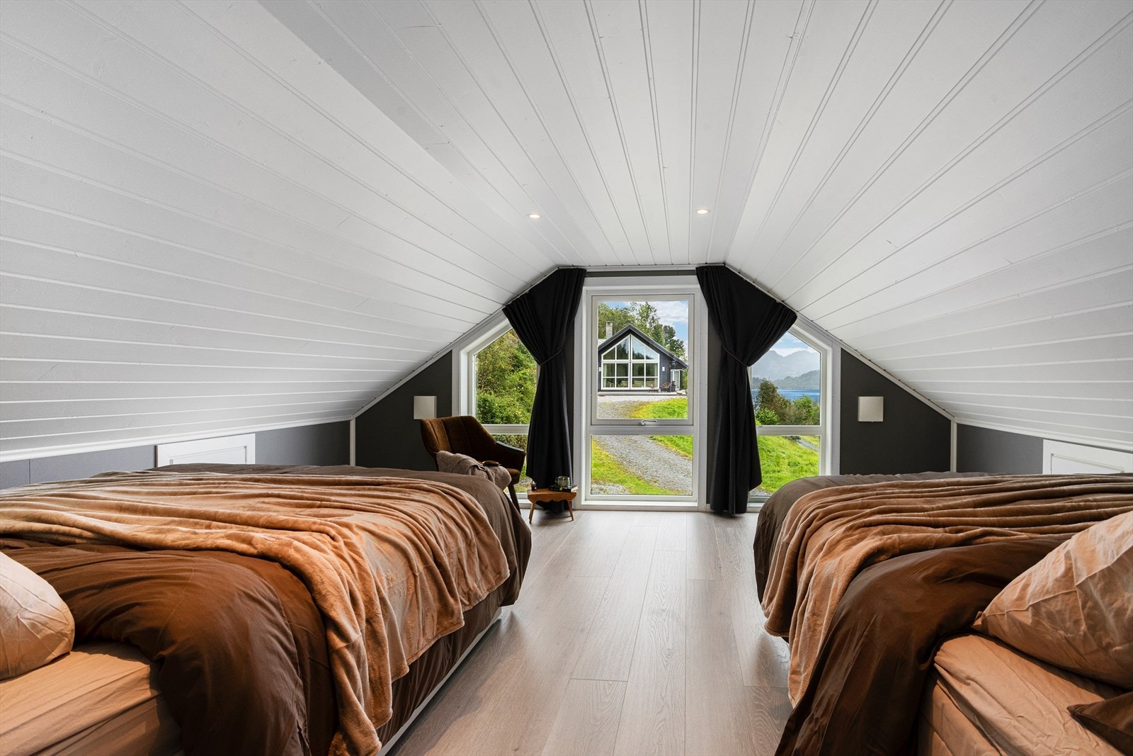 Innreidd loftsrom med soveplassar og gavlvegg med flott utsyn mot fjorden. Galleribilde