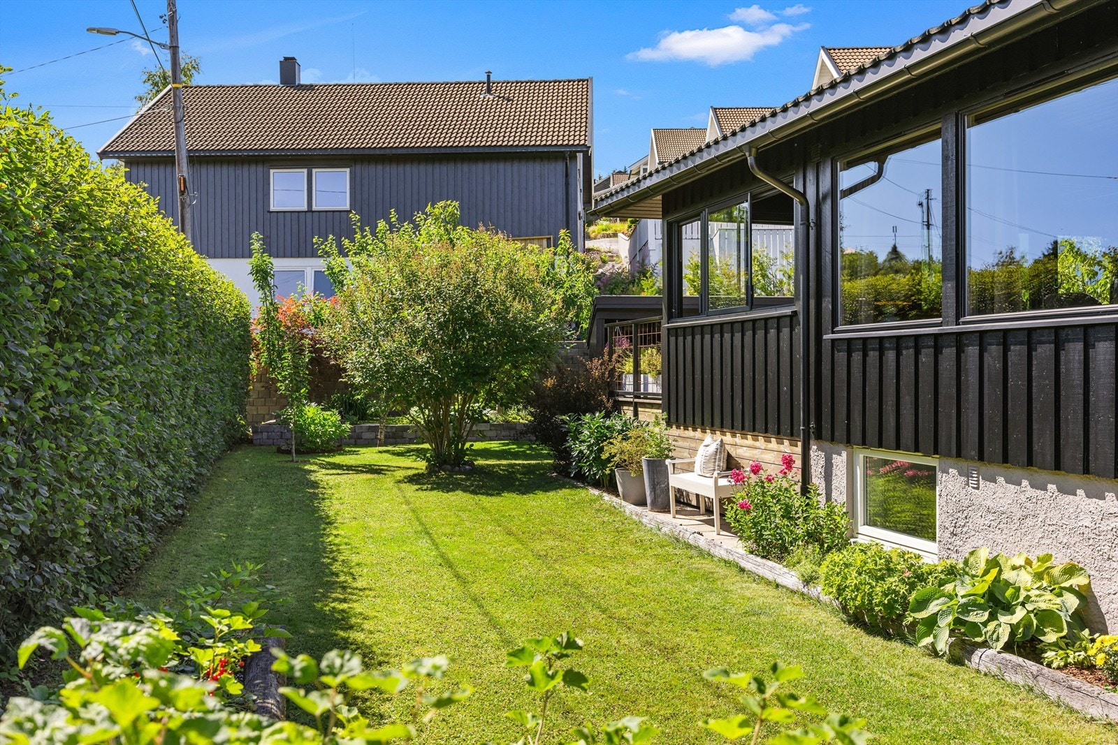 Den velholdte hagen er pent opparbeidet med plen og beplantning som skaper et grønt og innbydende utemiljø. Galleribilde