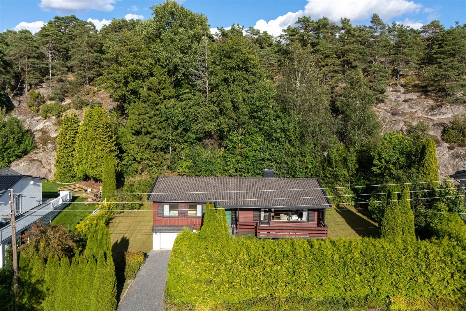Terrenget skråner svakt, med en bergknaus og tett skog som naturlig bakteppe mot øst - her kan man plante, bygge og forme uteområdet fritt, enten målet er kjøkkenhage, lekeplass eller nye sittegrupper i solen. Galleribilde