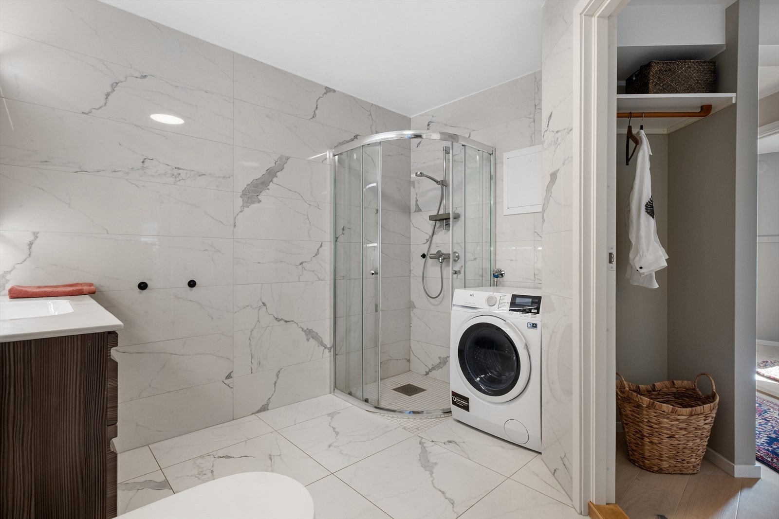 Badet er utstyrt med vegghengt toalett, baderomsinnredning, speilskap, dusjhjørne og opplegg for vaskemaskin. Galleribilde