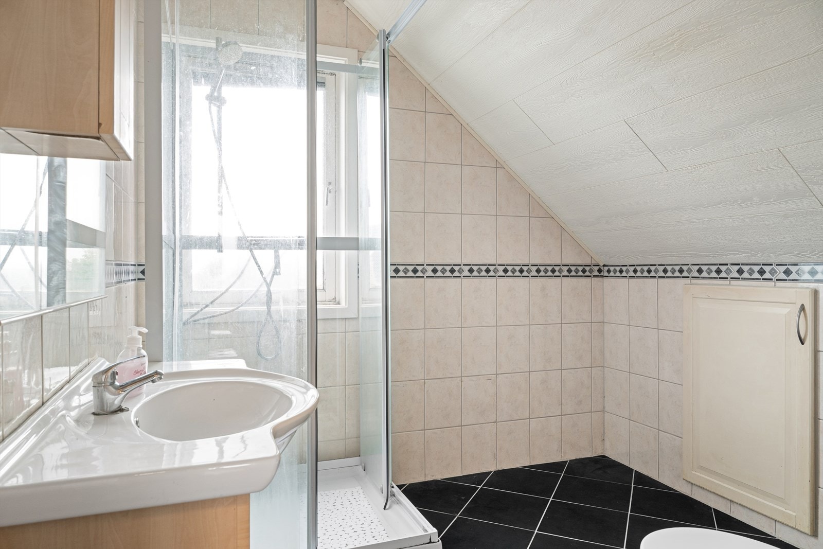 Badet er flislagt og innredet med toalett, baderomsinnredning og dusjkabinett. Galleribilde