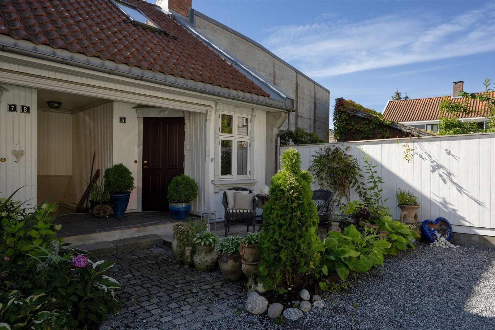 Brosteinsbelagt adkomst og frodige beplantninger rundt inngangen. Galleribilde