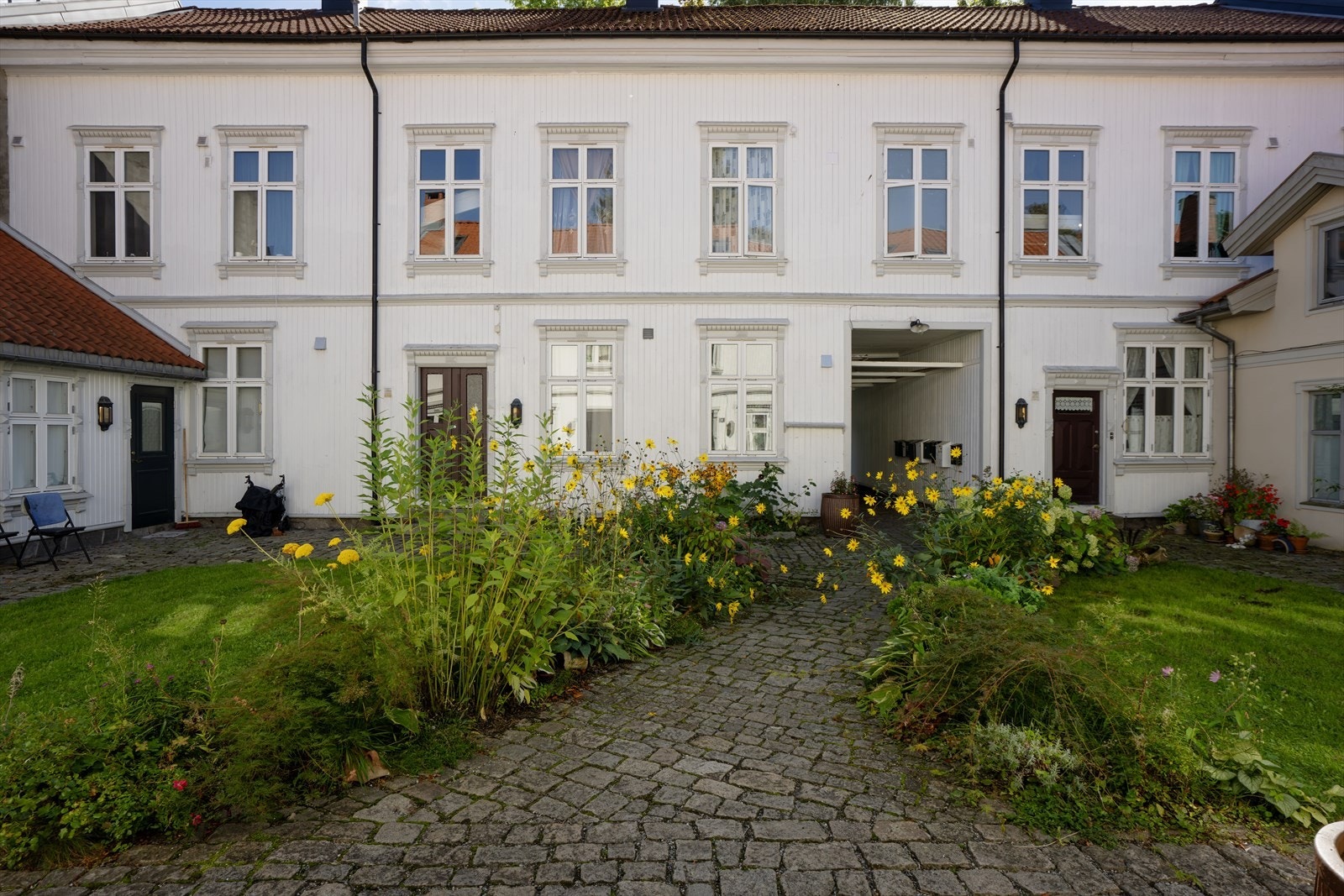 Felles bakgård omkranset av velholdt trehusbebyggelse og blomsterbed. Galleribilde