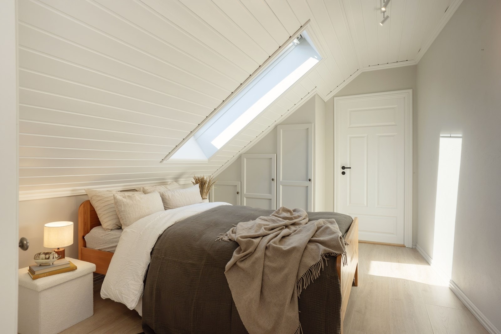 Hovedsoverommet har skråtak med hvitmalt panel og takvindu. Galleribilde