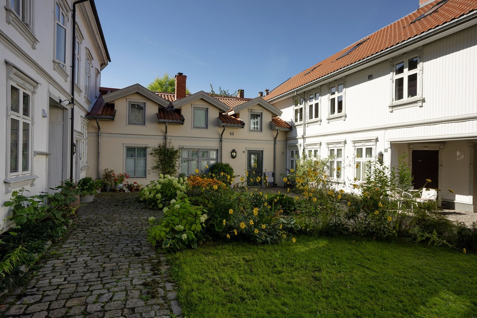 Idyllisk og bilfritt tun med gressplen og brosteinsganger. Galleribilde