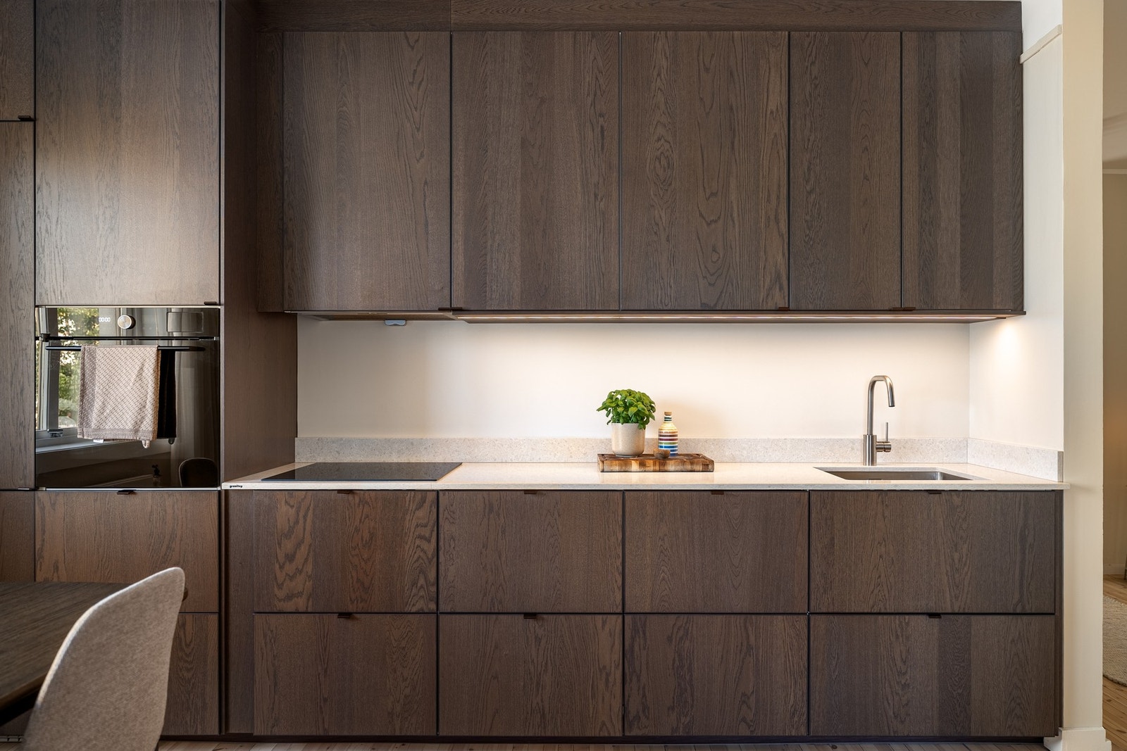 Et gjennomført kjøkken med spesialbestilt benkeplate og backsplash i komposittstein fra Granitop. Galleribilde