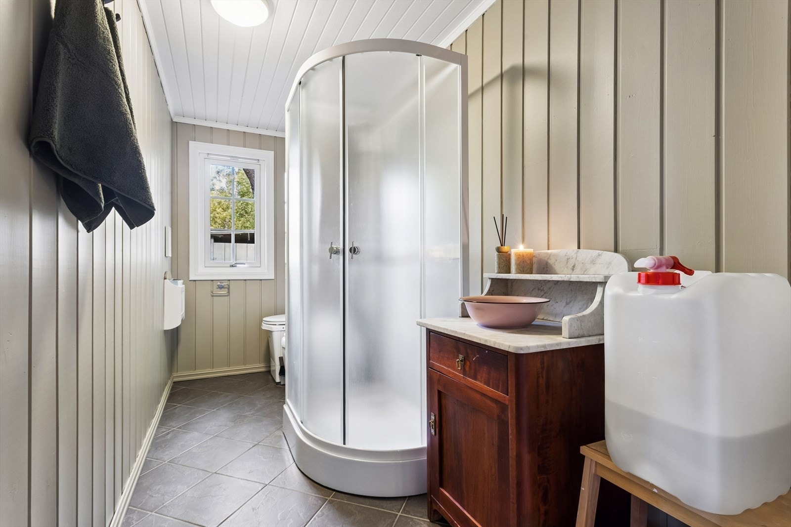 Badet er innredet med dusjkabinett, servantmøbel og mørke gulvfliser. Forbrenningstoalett og urinal gjør at du slipper å måtte gå ut for å gjøre ditt ærende. Galleribilde