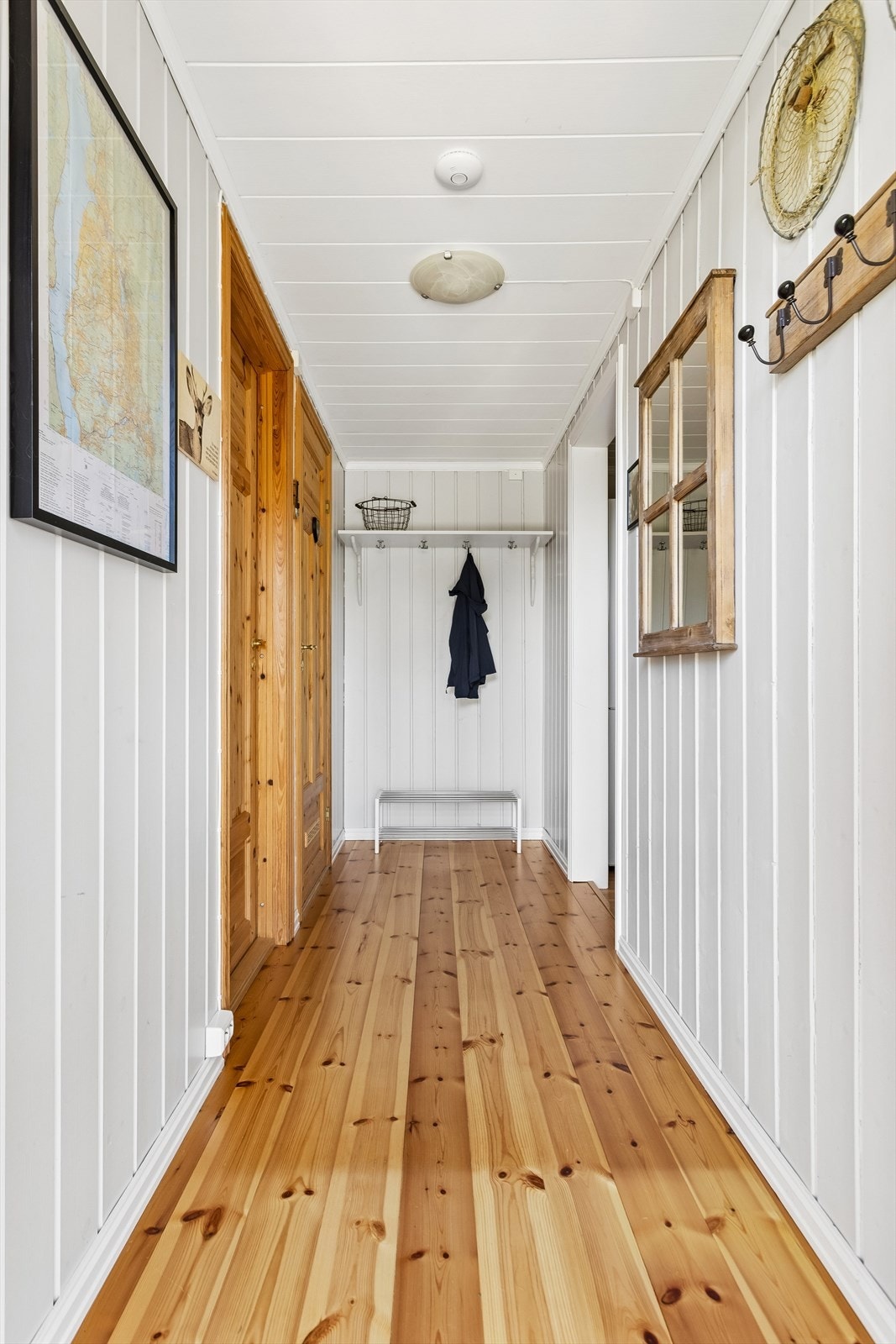 Entréen har tregulv, lyse panelvegger og plass til å henge fra seg yttertøy. Galleribilde