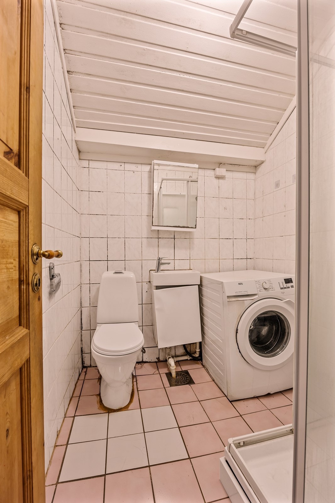 Flislagt bad med dusjkabinett, veggmontert servantinnredning, gulvstående toalett og opplegg for vaskemaskin. Galleribilde