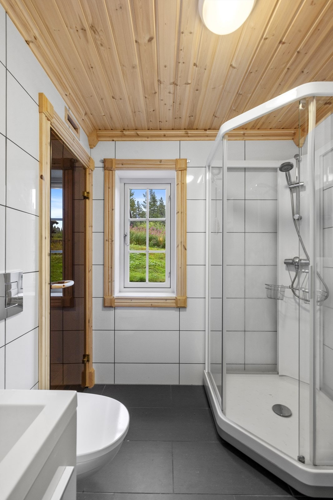 Lyst, helfliset baderom med varmekabler i gulv. Fra badet er det inngang til badstue Galleribilde